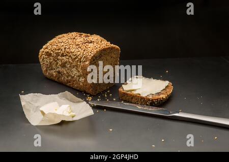 Homemade square bread made from gluten-free flour with sesame seeds. slice of bread with butter. concept is a home bakery. Stock Photo