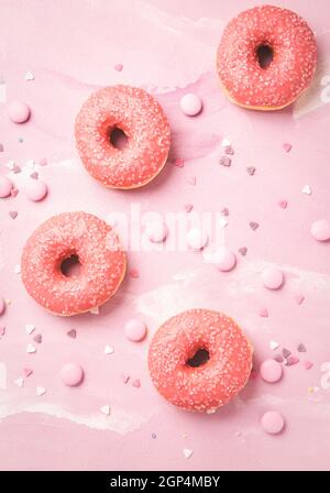 Donuts with pink icing and pink chocolate beans on pink background Stock Photo