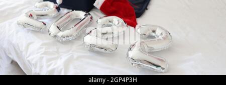 Numbers 2022 and collected suitcase with things with santa claus hats lie on bed Stock Photo