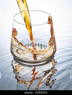 In a glass poured whiskey. Glass on the background of white and water. Stock Photo