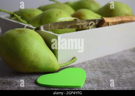 Selective focus shot of green pears in a ceramic plate and on the gray surface Stock Photo