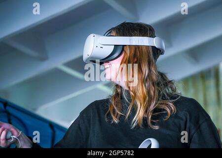 Young woman using Oculus virtual reality gaming headset viewer. Stock Photo