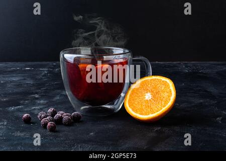 Teacup with halved orange and frozen currant berries Stock Photo