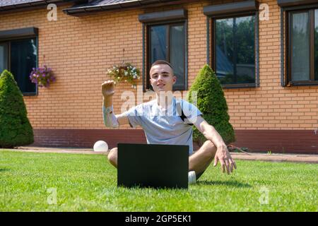Man sits on lawn and using laptop Stock Photo