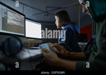 Male and female hackers works on computers in darknet, dangerous teamwork. Illegal web programmer at workplace, criminal occupation. Data hacking, cyb Stock Photo