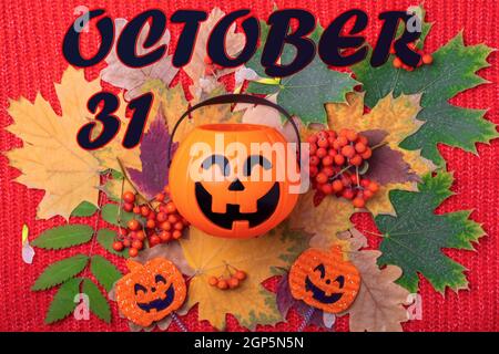 October 31st is the date for Halloween. Halloween Jack o Lantern with candies on a colorful autumn background of dried leaves, berries. Halloween holi Stock Photo