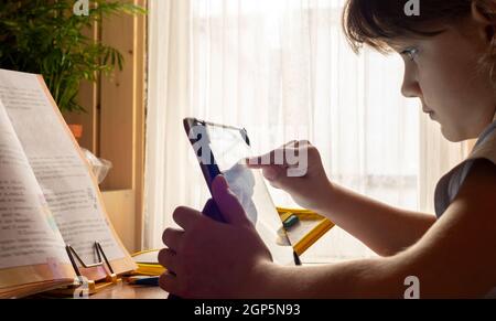 Girl studying online at home using tablet computer Stock Photo