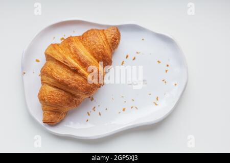 White handmade clay plate with fresh croissant on a white table Stock Photo