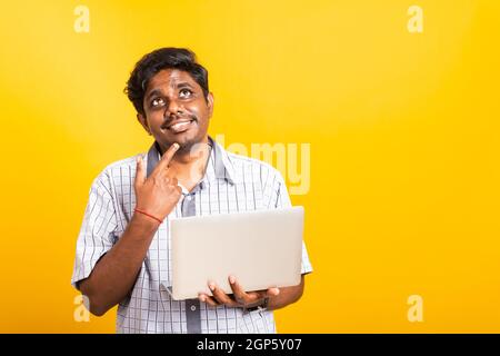 Closeup Asian happy portrait young black man holds a laptop computer hand finger handle on the chin and thinking question looking away, studio isolate Stock Photo