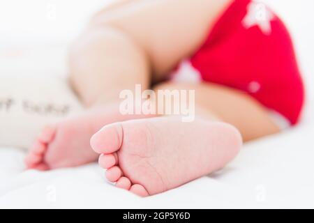 Portrait of beautiful Asian newborn little baby sleeping on white bed at home, Happy baby wears a red shirt relaxing pillow in the room, Family mornin Stock Photo