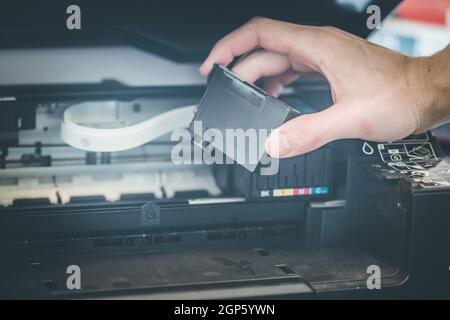 Putting new printer cartridge into the printer, inkjet. Stock Photo