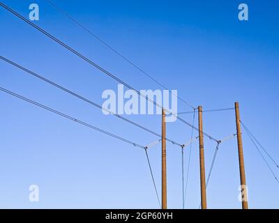 View of the electricity wires on the wooden poles in the street on a sunny day Stock Photo