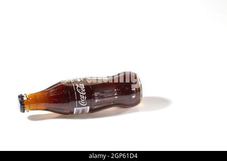 Close up view of lying Coca Cola in glass bottle isolated on white background. Sweden. Uppsala. Stock Photo