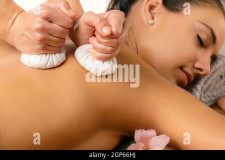 Close up portrait of attractive woman having ayurvedic pinda massage on back. Stock Photo