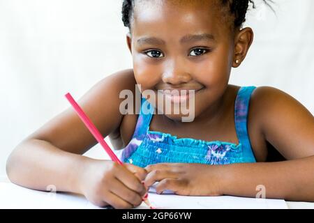 Close up face shot of african kid holding red pencil.Isolated on white background. Stock Photo