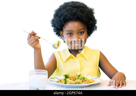 Close up portrait of cute african girl with afro hairstyle eating healthy vegetable dish. Isolated on white.
