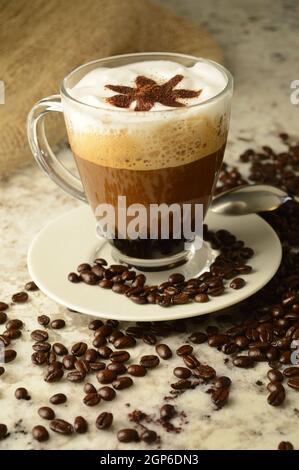 A specialty brewed cup of coffee in a scene of coffee beans and a marble countertop. Stock Photo