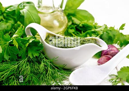 Sauce of dill, parsley, basil, cilantro, other spicy herbs, garlic and vegetable oil in a gravy boat, a spoon with coarse salt on the background of li Stock Photo