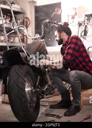 Vertical shot of a German male repairing his motorcycle. Stock Photo