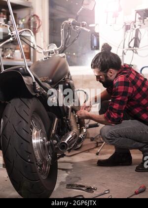 Vertical shot of a German male repairing his motorcycle. Stock Photo