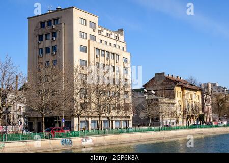 Bucharest, Romania, 13 February 2021 - Landscape with large old trees and old buildings near Dambovita river and clear blue sky in the center of Bucha Stock Photo