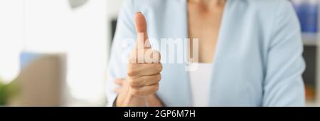 Businesswoman in suit holds thumbs up in office Stock Photo