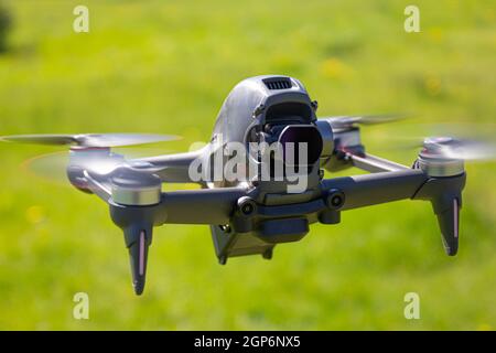 New FPV drone is flying during a sunny day on grass in beckground. Top Front View. Headless Quadcopter with Digital 4K 60 fps camera and Remote Contro Stock Photo