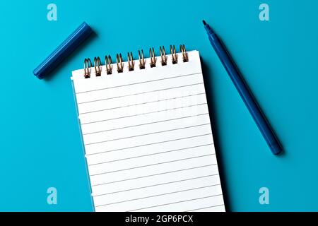 template for text and design. empty white notepad and one marker on blue background Stock Photo