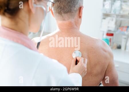 Doctor using stethoscope to check lung function on back of man Stock Photo