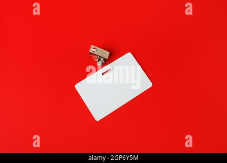 White ID card. Blank security badge on red paper background. Copy space for text. Stock Photo