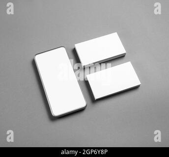 Smartphone and blank business cards on gray paper background. Branding mock up. Stock Photo