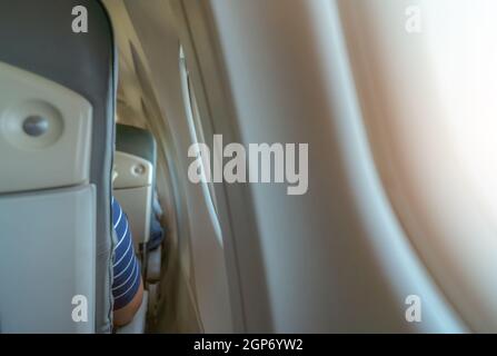 Rearview of airplane seat near plane window. Economy class airplane. Inside of commercial airline. Small space between passenger economy seat and wind Stock Photo