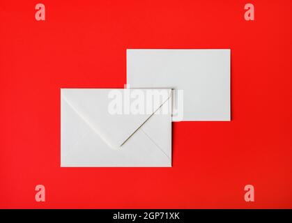 Two blank paper envelopes on red paper background. Back and front. Top view. Flat lay. Stock Photo