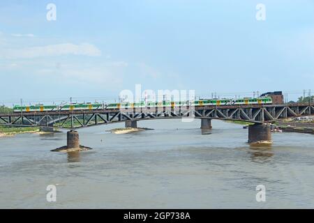 Long bridge over Wisla in Warsaw. Modern bridge over Wisla River in Warsaw. Landscape with river and bridge in city. Passenger train rides over the br Stock Photo