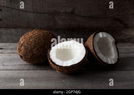 Broken coconuts on gray wooden background. White coconut pulp. High quality photo Stock Photo