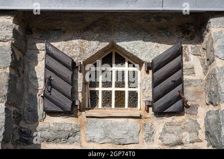 Old window with solid wood shutters and a stone wall in the Alps in France Stock Photo
