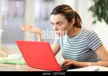 Stunned student watching laptop content complaining at home Stock Photo