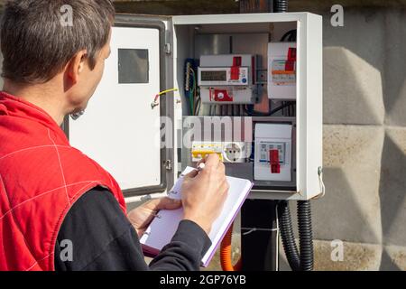 An electrician takes control readings of electricity meters Stock Photo