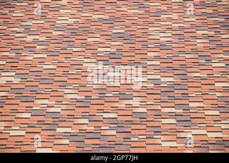 Roof from multi-colored bituminous shingles. Patterned bitumen shingles Stock Photo