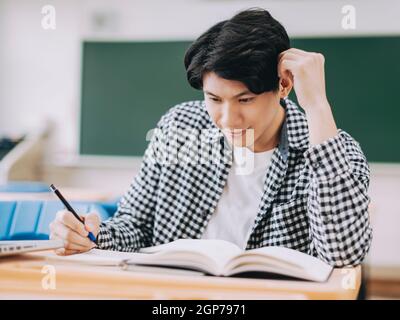 Young cheerful asian student studying in classroom Stock Photo - Alamy