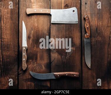 set of different kitchen knives with wooden handles on a brown background from boards, copy space Stock Photo