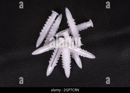 A group of plastic anchors on a black surface Stock Photo