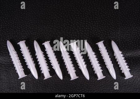 A group of plastic anchors organized in a row on a black surface Stock Photo