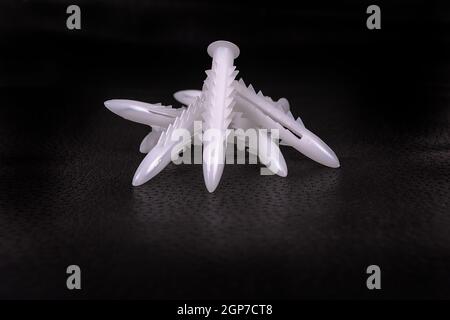 A group of plastic anchors on a black surface Stock Photo