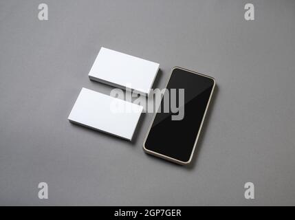 Smartphone and blank business cards on gray paper background. Blank branding mockup. Stock Photo