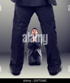 The boss dismisses the employee who asks for help kneeling. Stock Photo