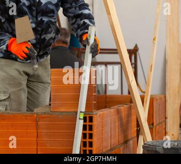 Bricklayer industrial worker installing brick masonry on interior wall with trowel putty knife Stock Photo