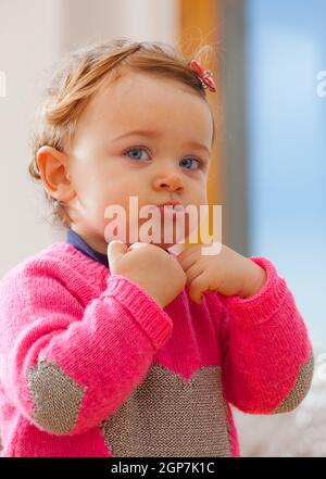 Toddler baby girl plays making bubbles with her mouth. Stock Photo