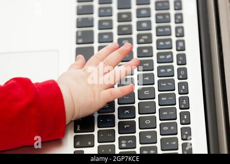 Hand of a newborn baby using a laptop keyboard. Stock Photo