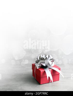 Single red gift box with silver ribbon on grey background. Stock Photo